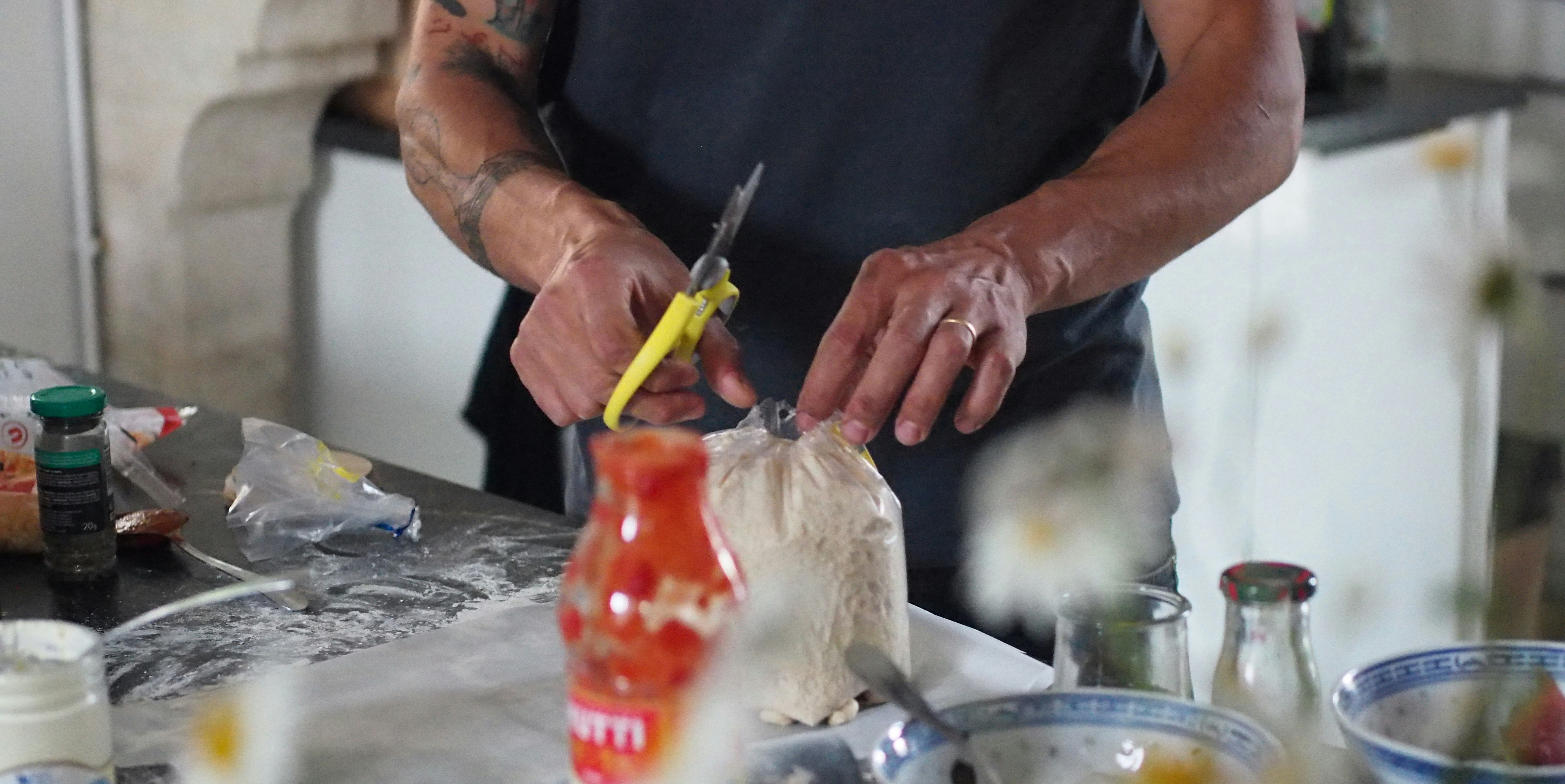 a man in a kitchen cutting a bag of food