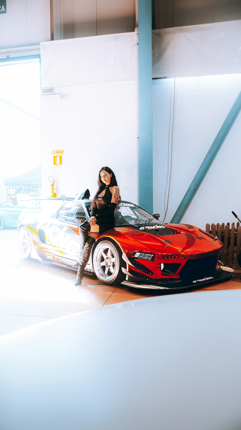 a woman sitting on top of a red sports car