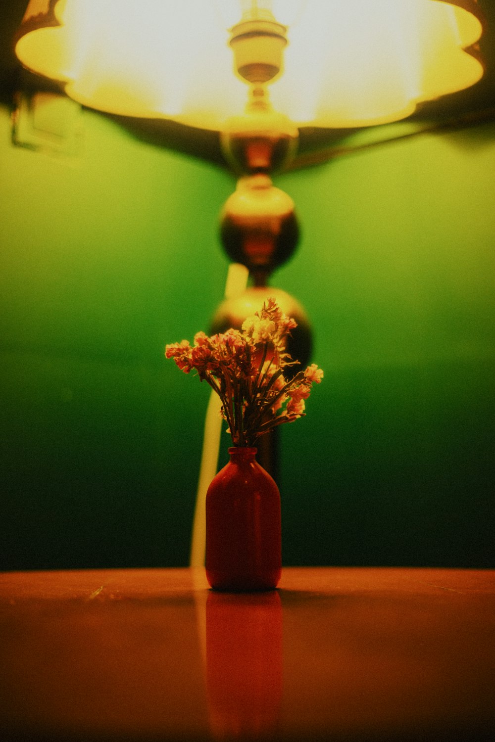 a red vase with flowers sitting on a table