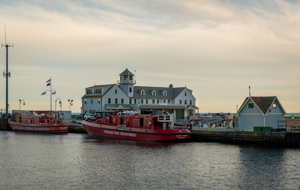 two red boats in the water next to a building