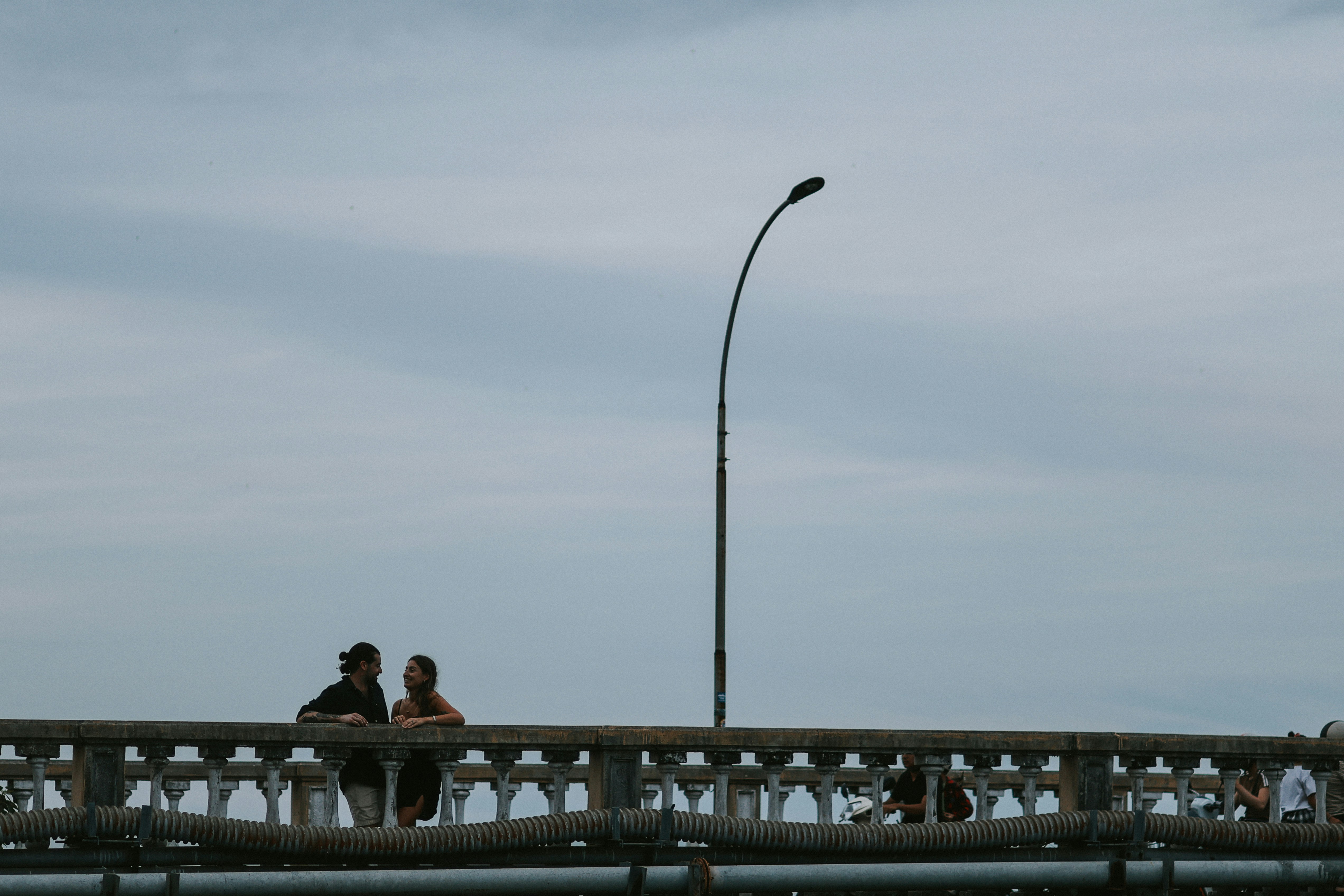 A group of people sitting on a bridge next to a street light photo – Free  Portrait Image on Unsplash