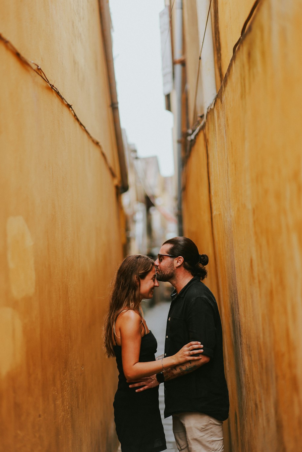 a man and a woman kissing in an alley