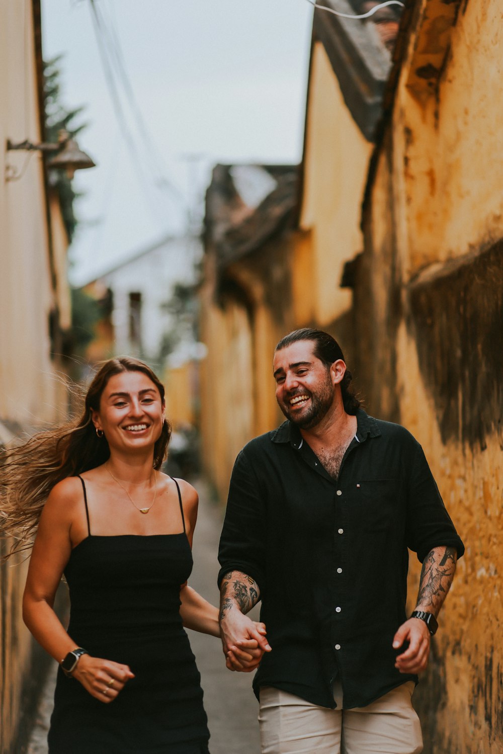 a man and woman walking down a street holding hands