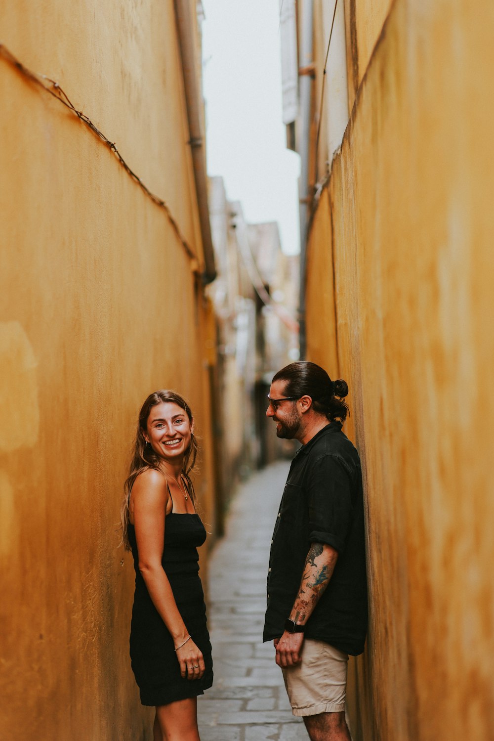 a man and a woman standing in a narrow alleyway