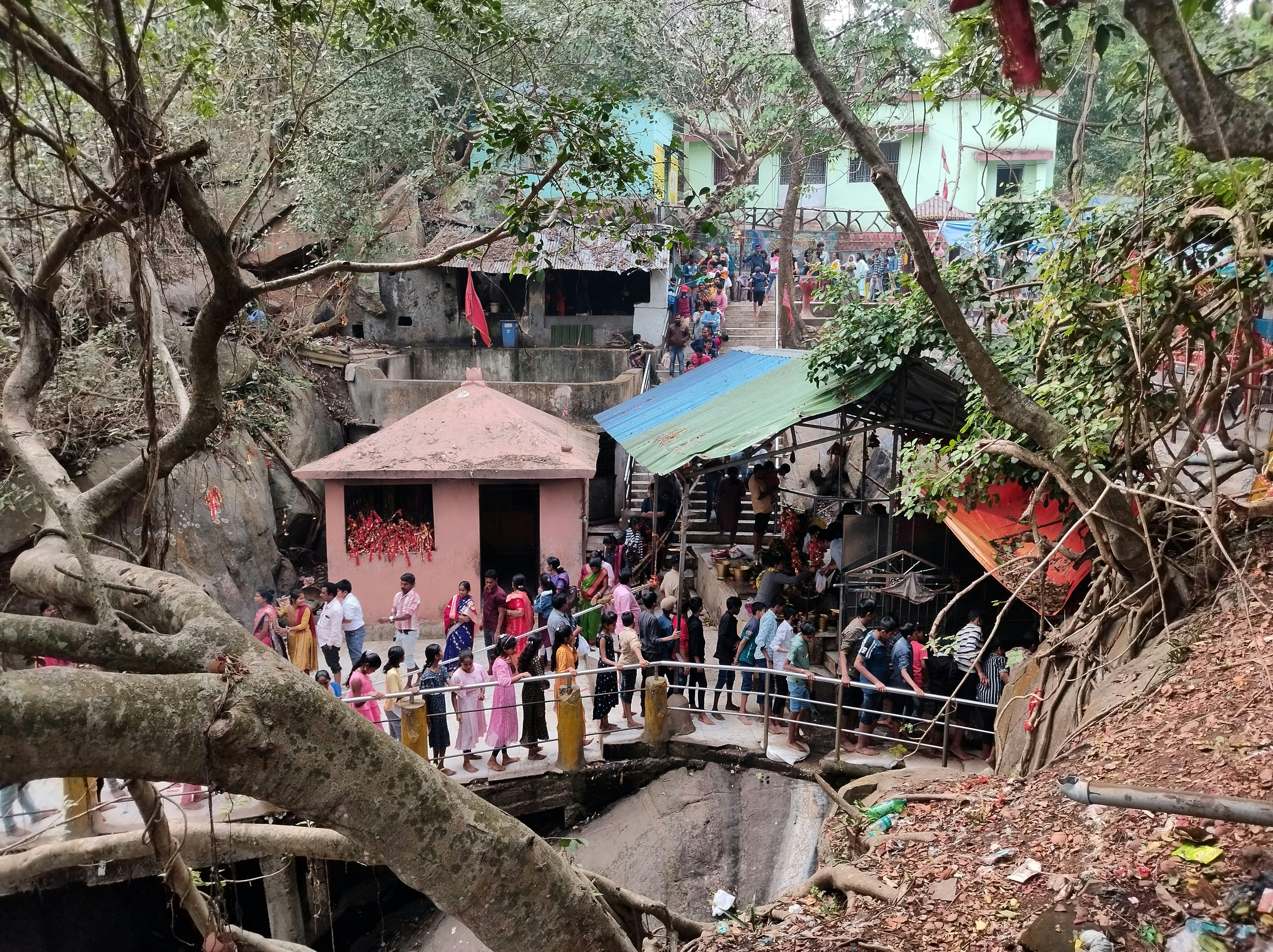 दूर से ड्रोन के साथ पहाड़ों के ऊपर उड़ते हुए और नीचे एक सर्च टीम को कठिन बर्फीले ढलान पर चढ़ते हुए दर्शाती तस्वीर।