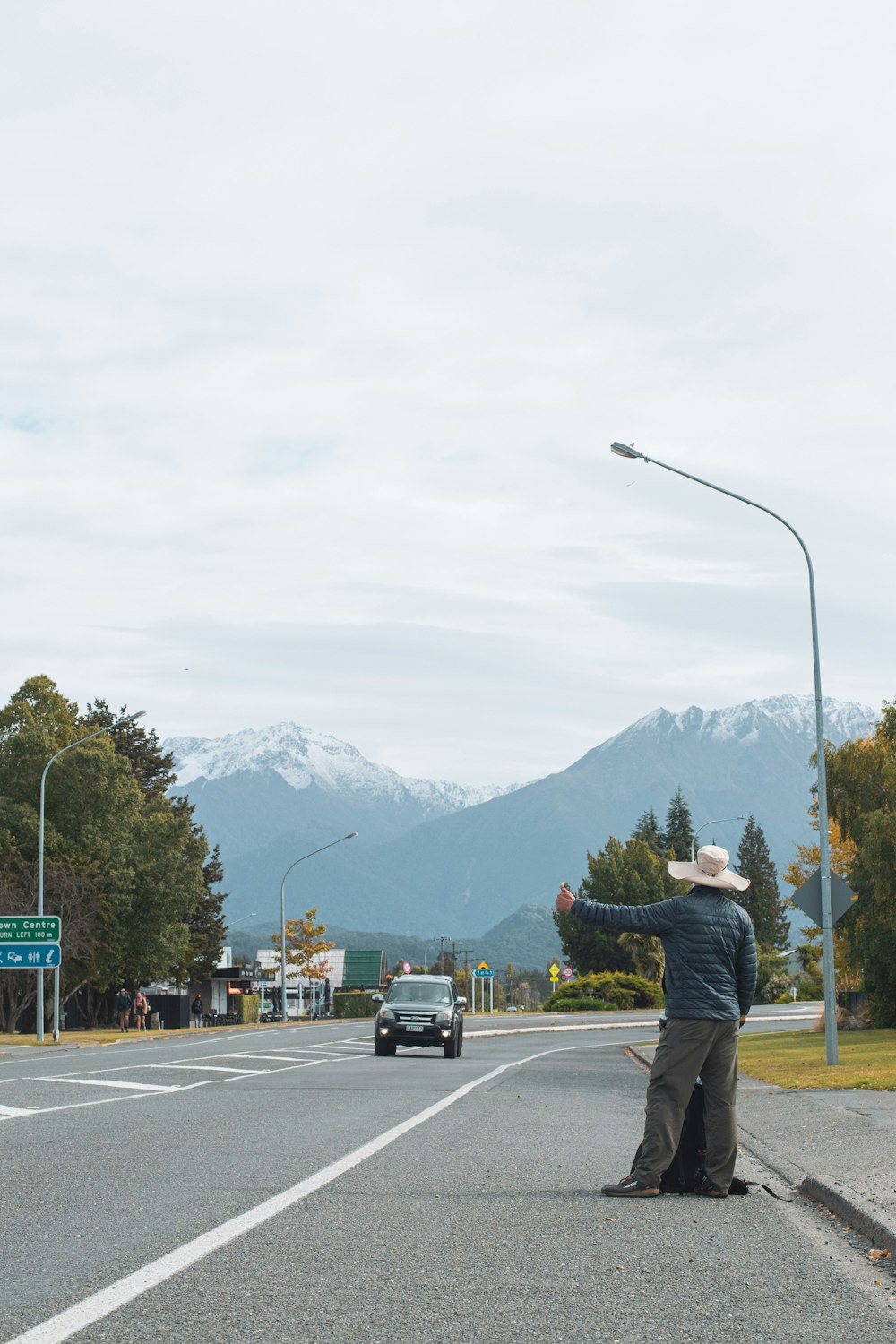 a man standing on the side of a road pointing at something