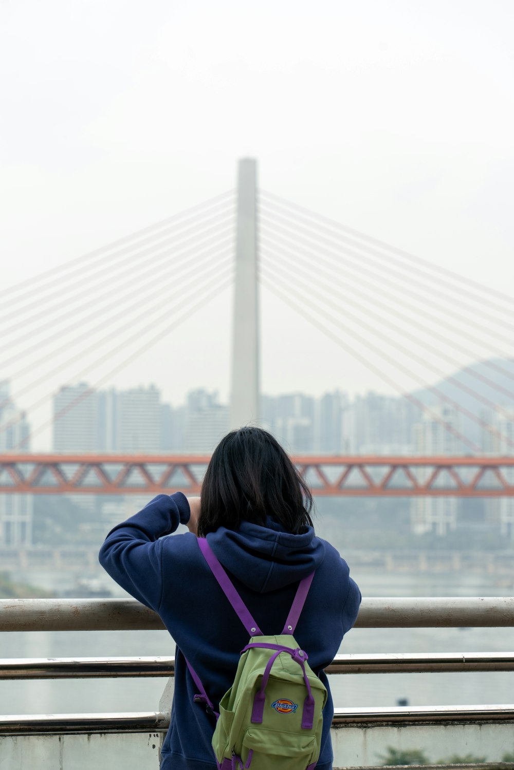 a woman sitting on a bench looking at a bridge