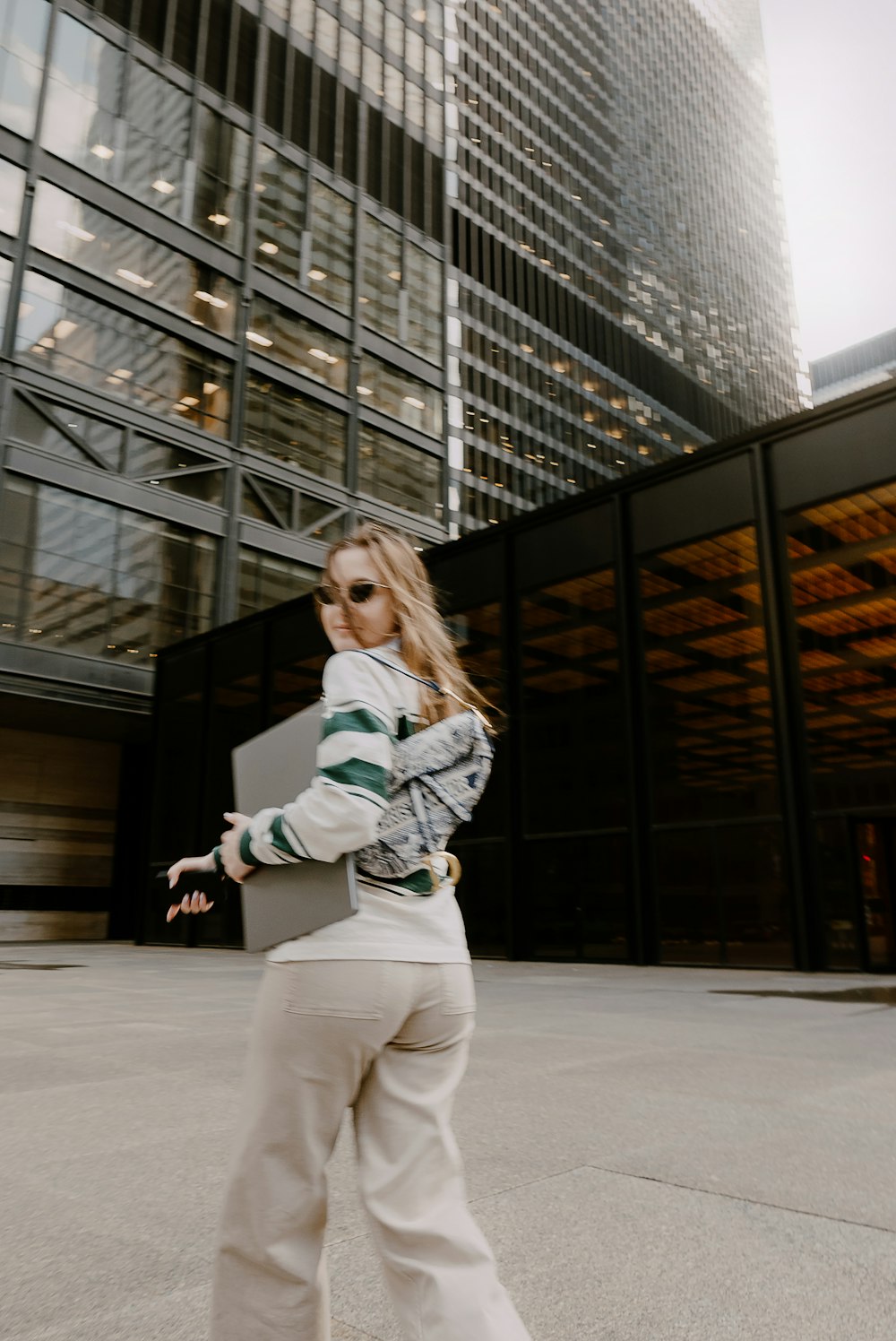 a woman walking down a sidewalk in front of a tall building