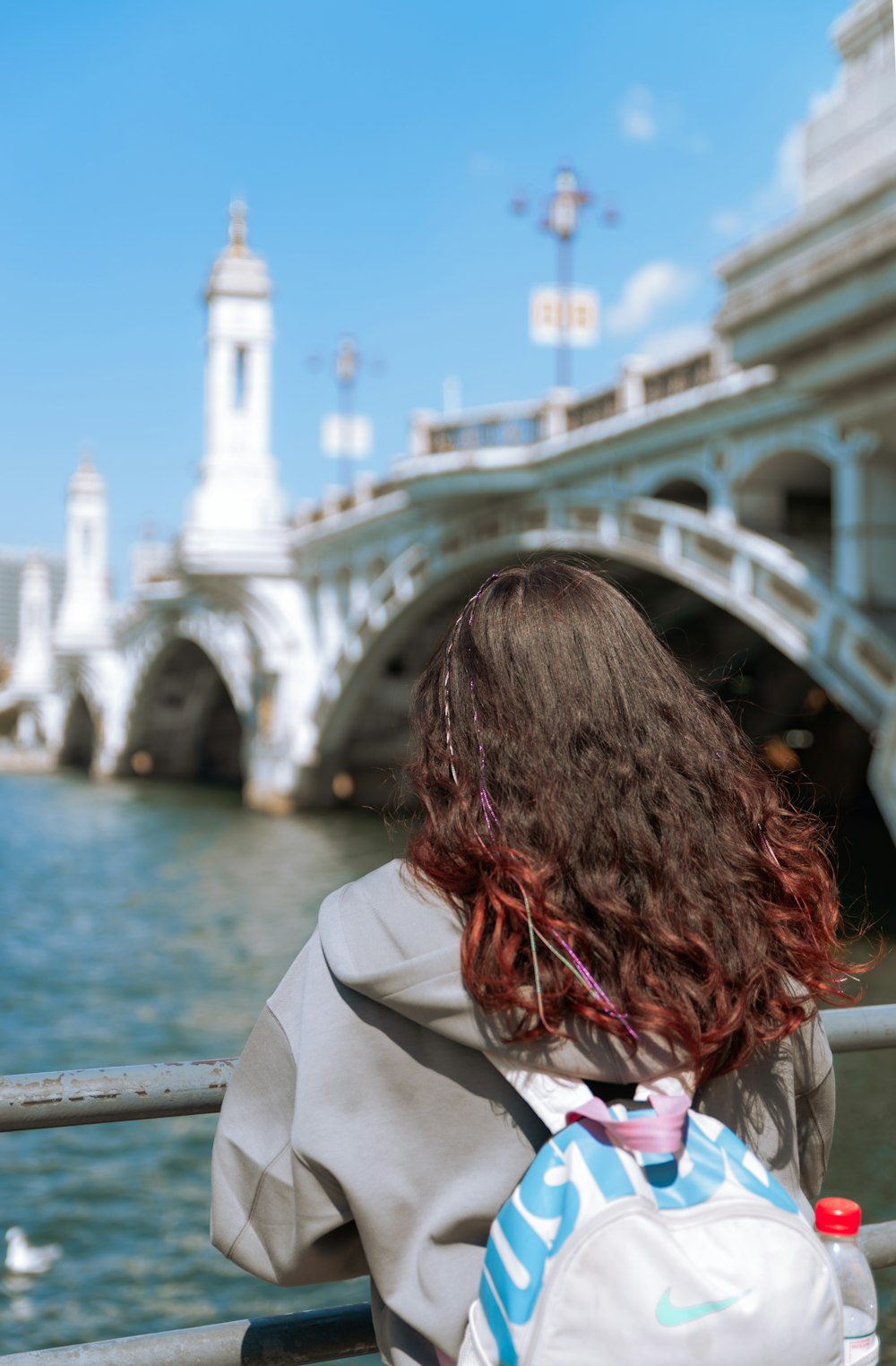 a woman with a backpack looking at the water