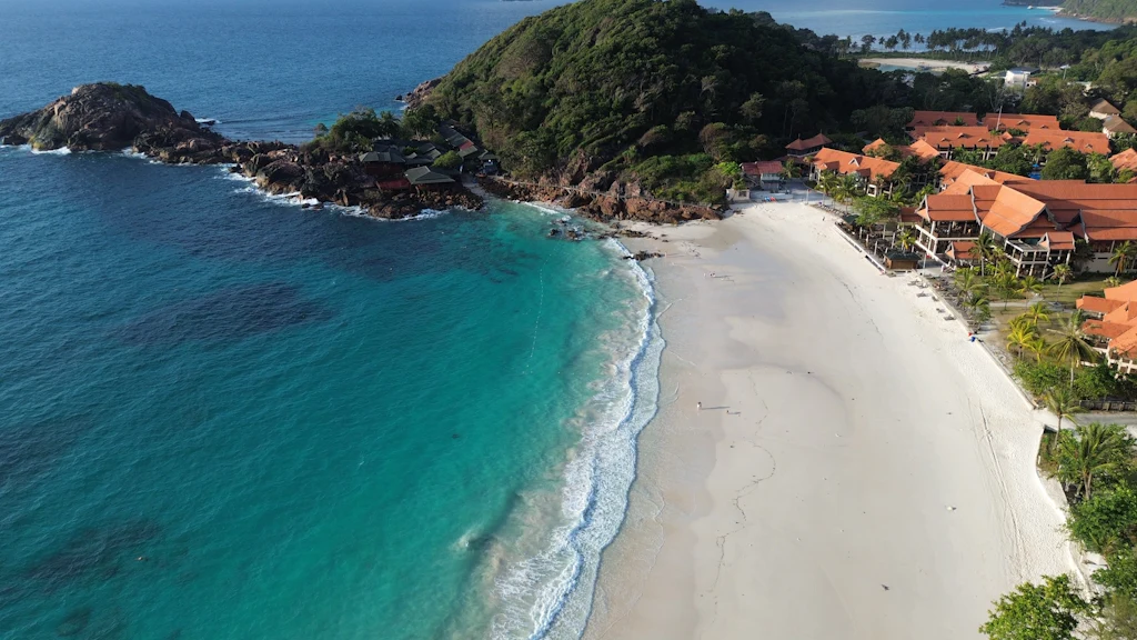 Aerial view of a white-sand bay, turquoise water and red-roofed resort buildings on Redang Island
