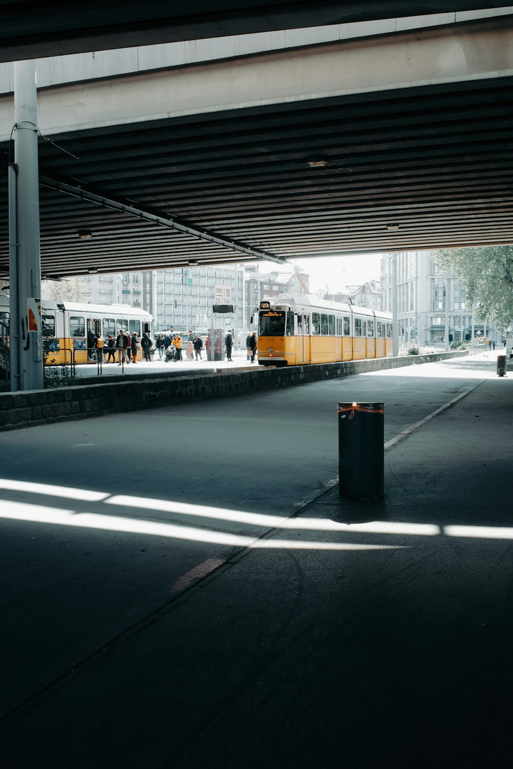 a yellow and white train traveling under a bridge