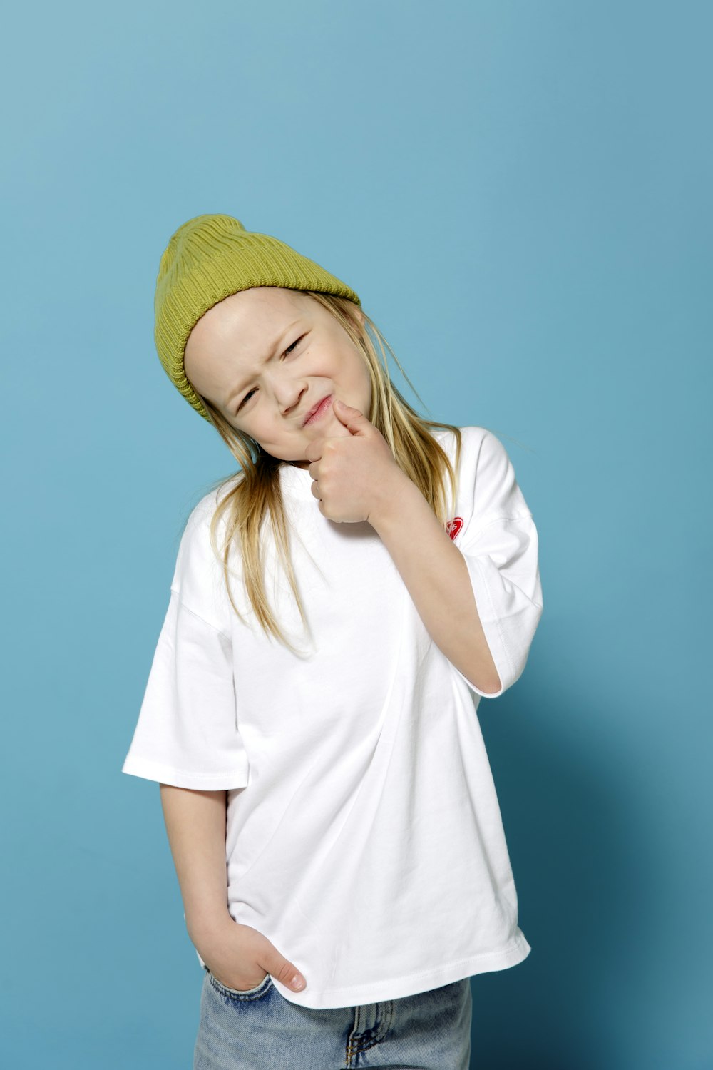 a young girl wearing a green hat posing for a picture