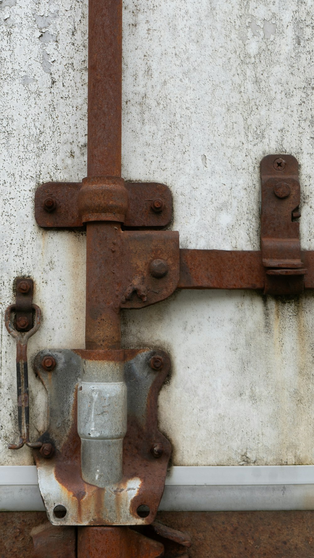 a rusted metal latch on the side of a building