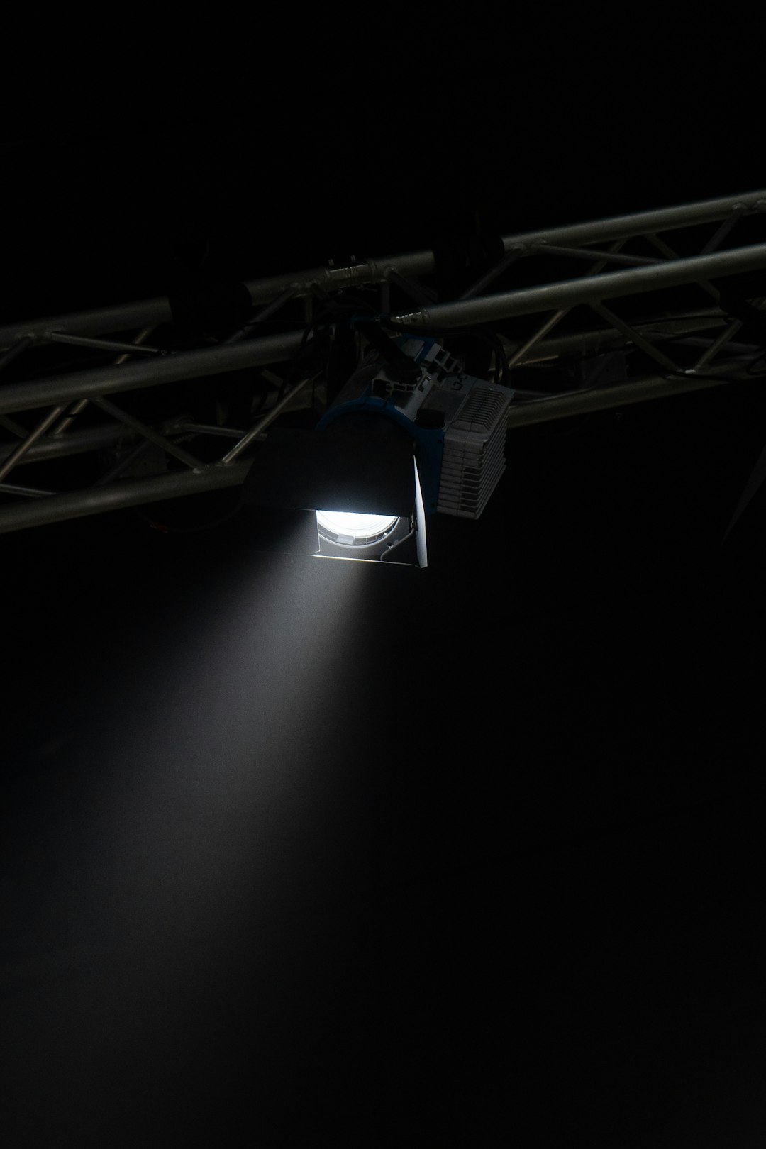 A dramatic image showcasing a drum set under a focused spotlight, casting deep shadows around.