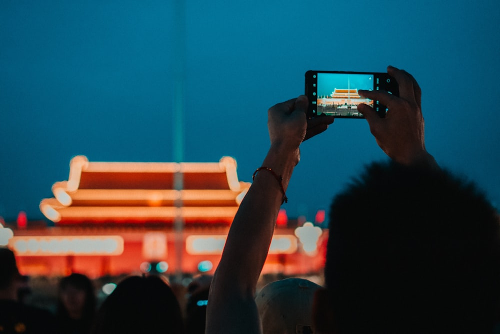a person taking a picture of a building at night
