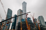 a large group of cranes standing in front of a tall building