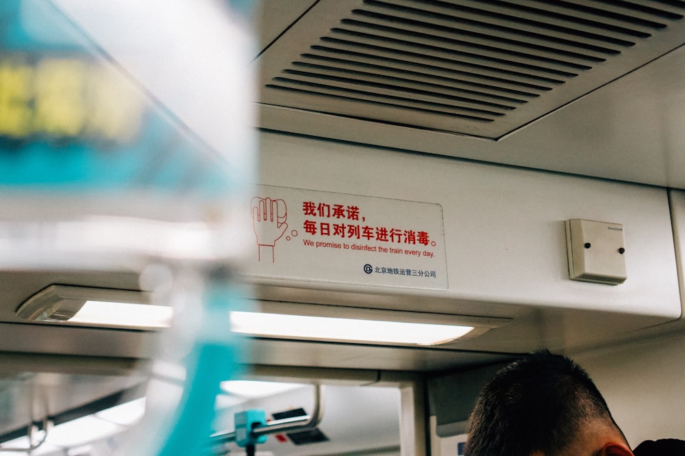 a man sitting on a train next to a sign