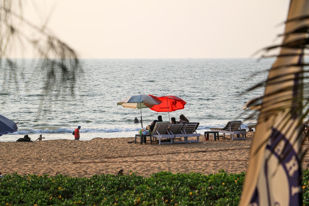 a group of people sitting on top of a sandy beach