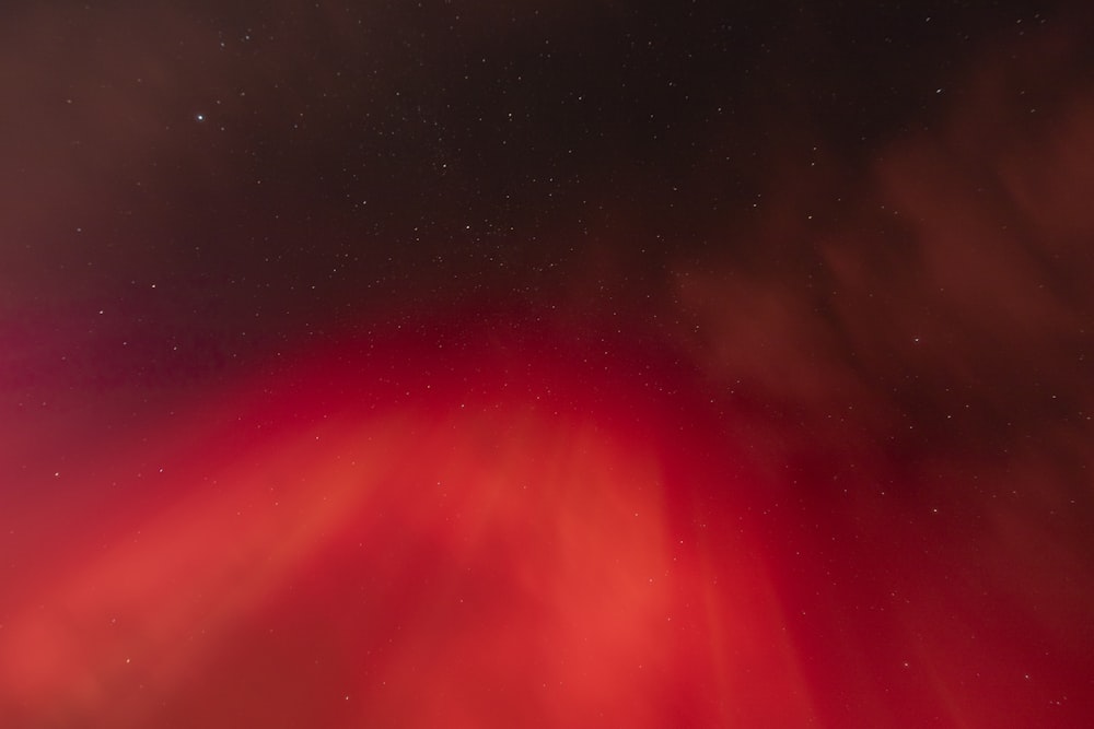 a red and black sky with stars and clouds