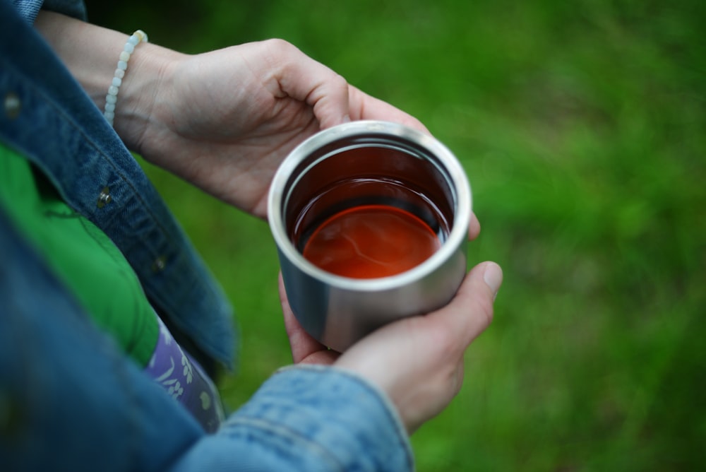 a person holding a cup of tea in their hands