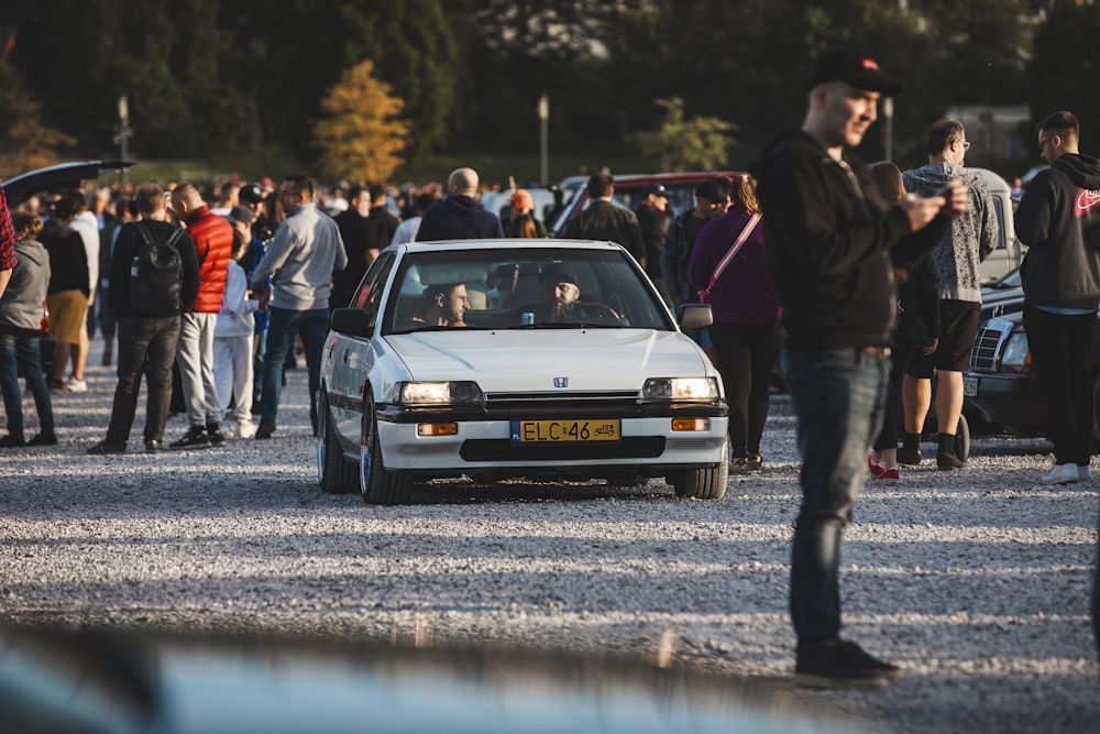 a group of people standing around a white car