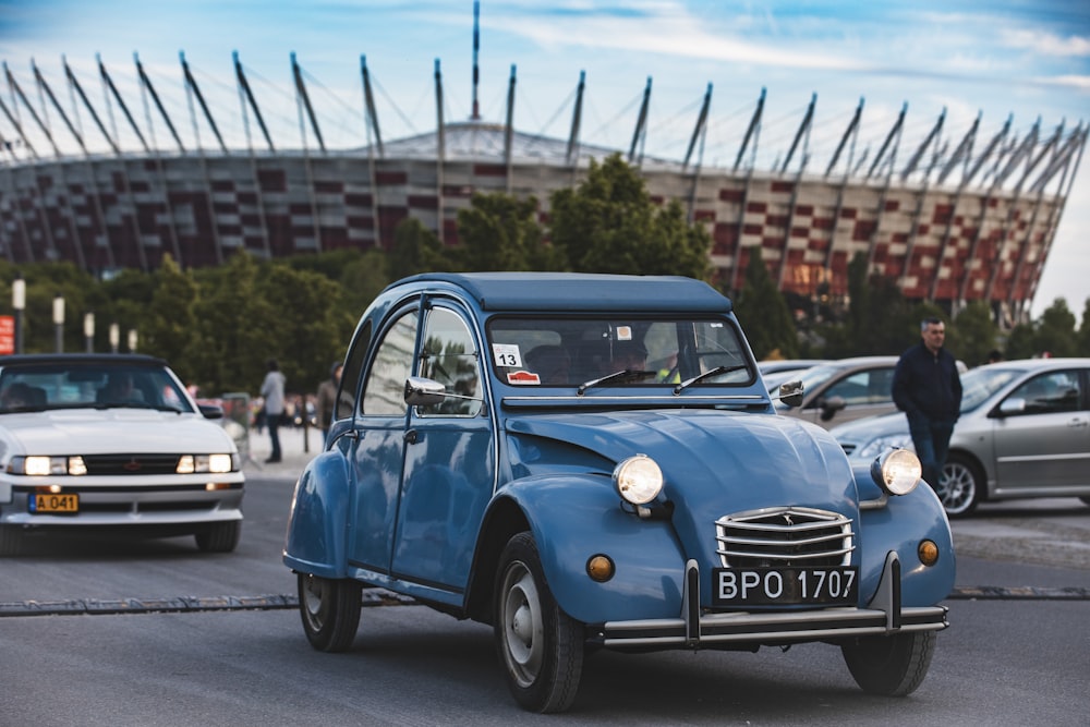 a blue car driving down a street next to other cars