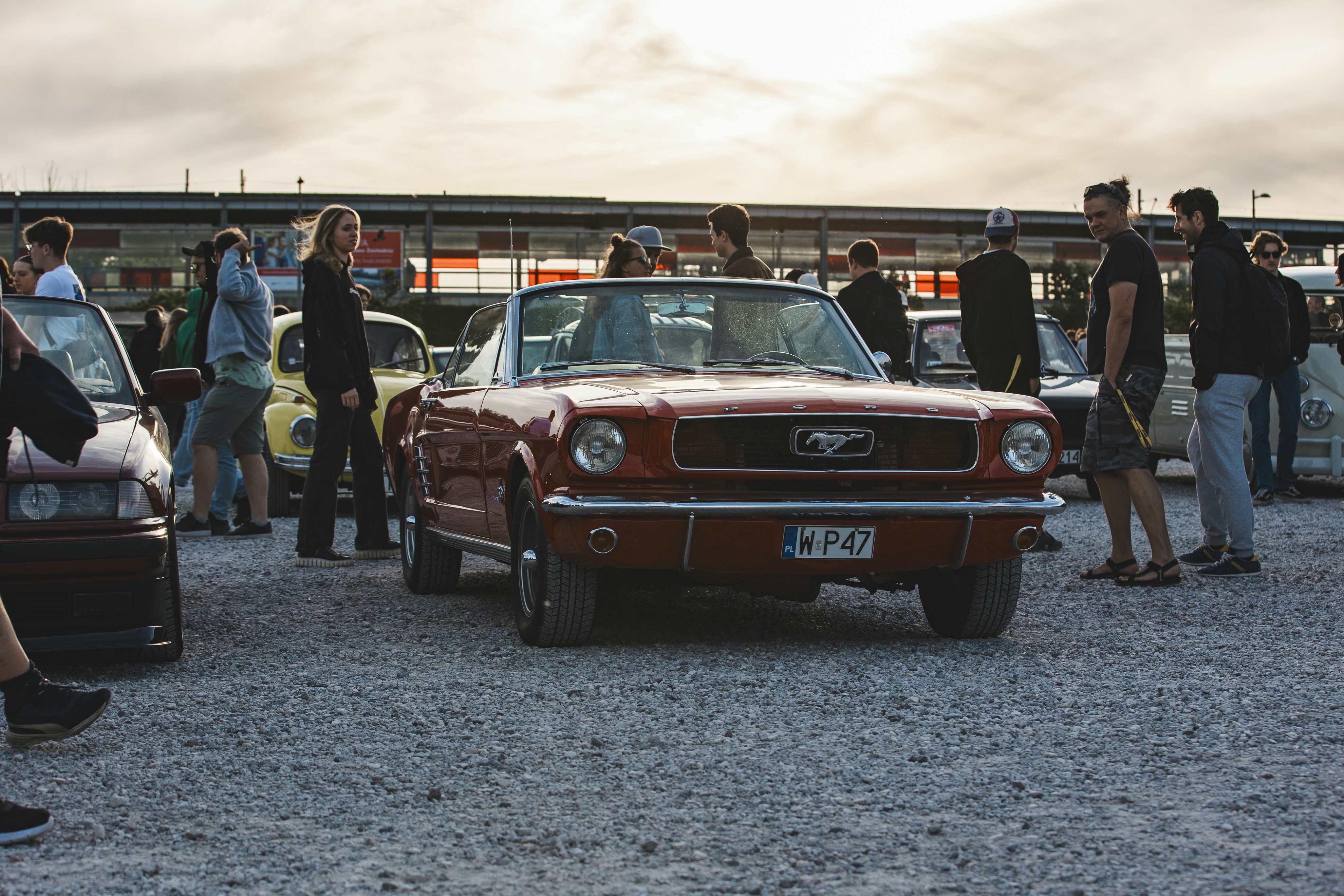 a group of people standing around a red car
