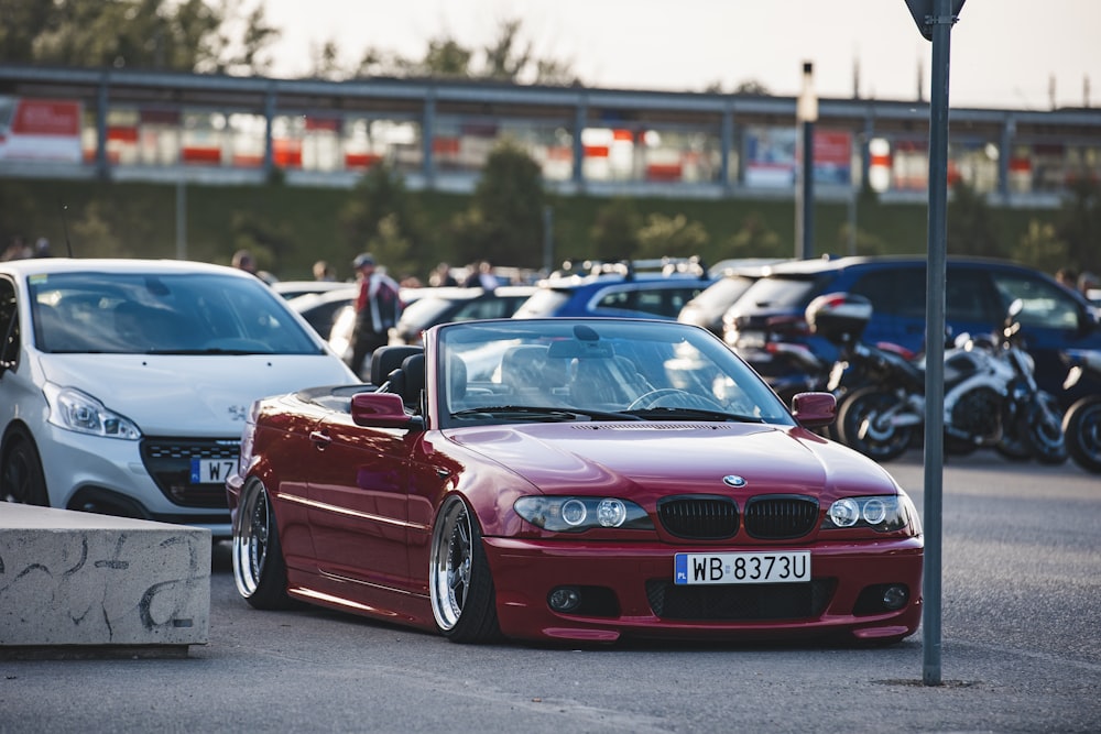 a red car parked next to a white car in a parking lot