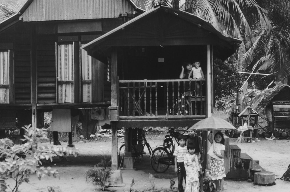 a group of people standing outside of a wooden house