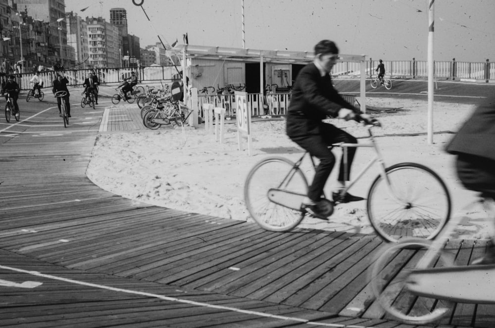 a black and white photo of a man riding a bike