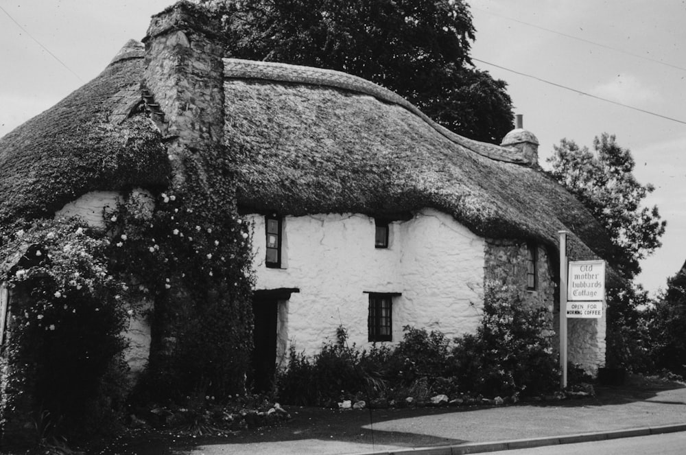 une photo en noir et blanc d’une maison avec un toit de chaume