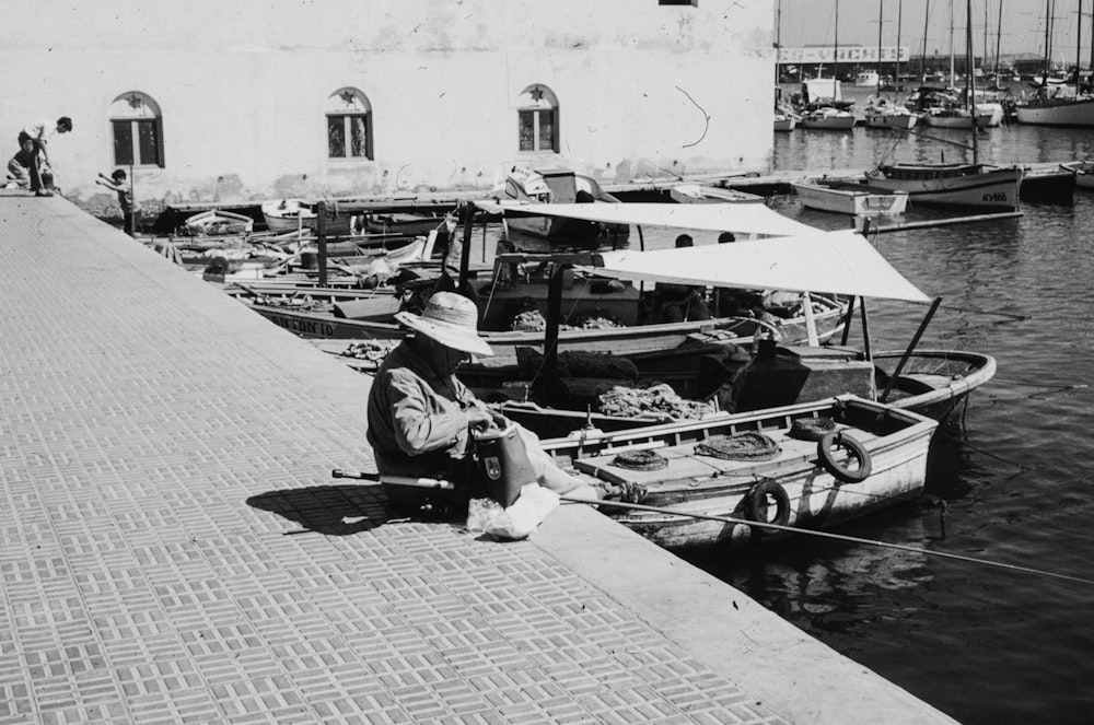 a man sitting on a dock next to a boat