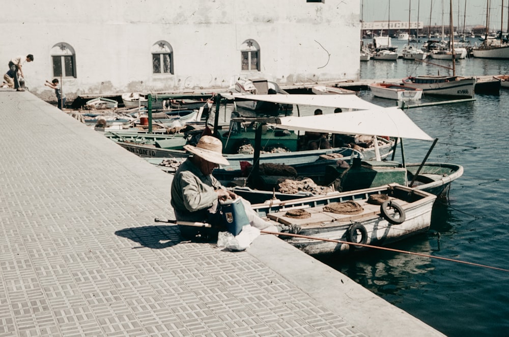 a man sitting on a dock next to a boat