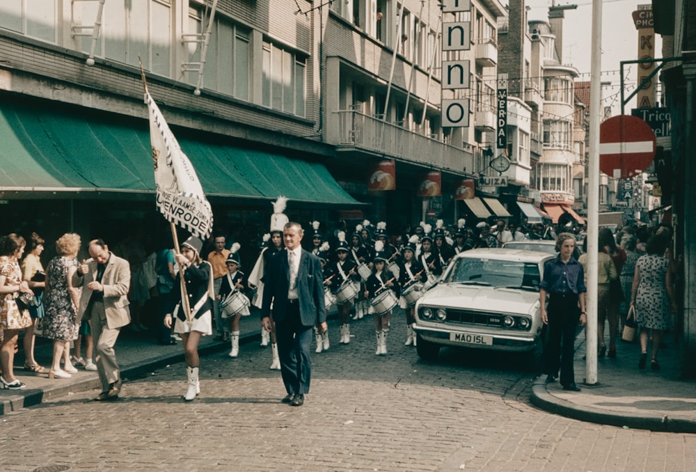 a group of people walking down a street next to a car