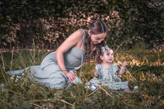 a woman and a child sitting in the grass