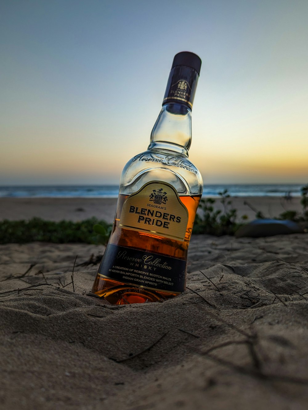 a bottle of blended rum sitting in the sand