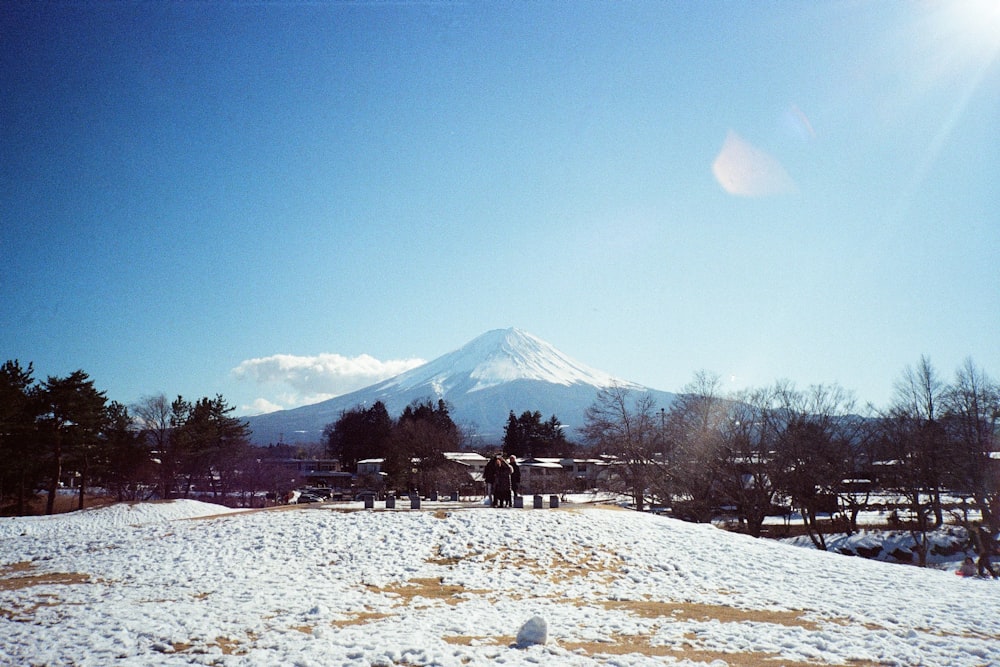 a snow covered field with a mountain in the background