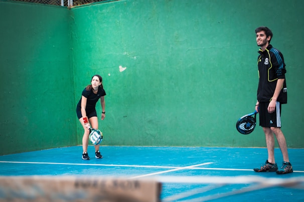 a man and woman standing on a tennis court holding racquets