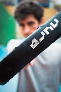 a man holding a black bat with white letters on it