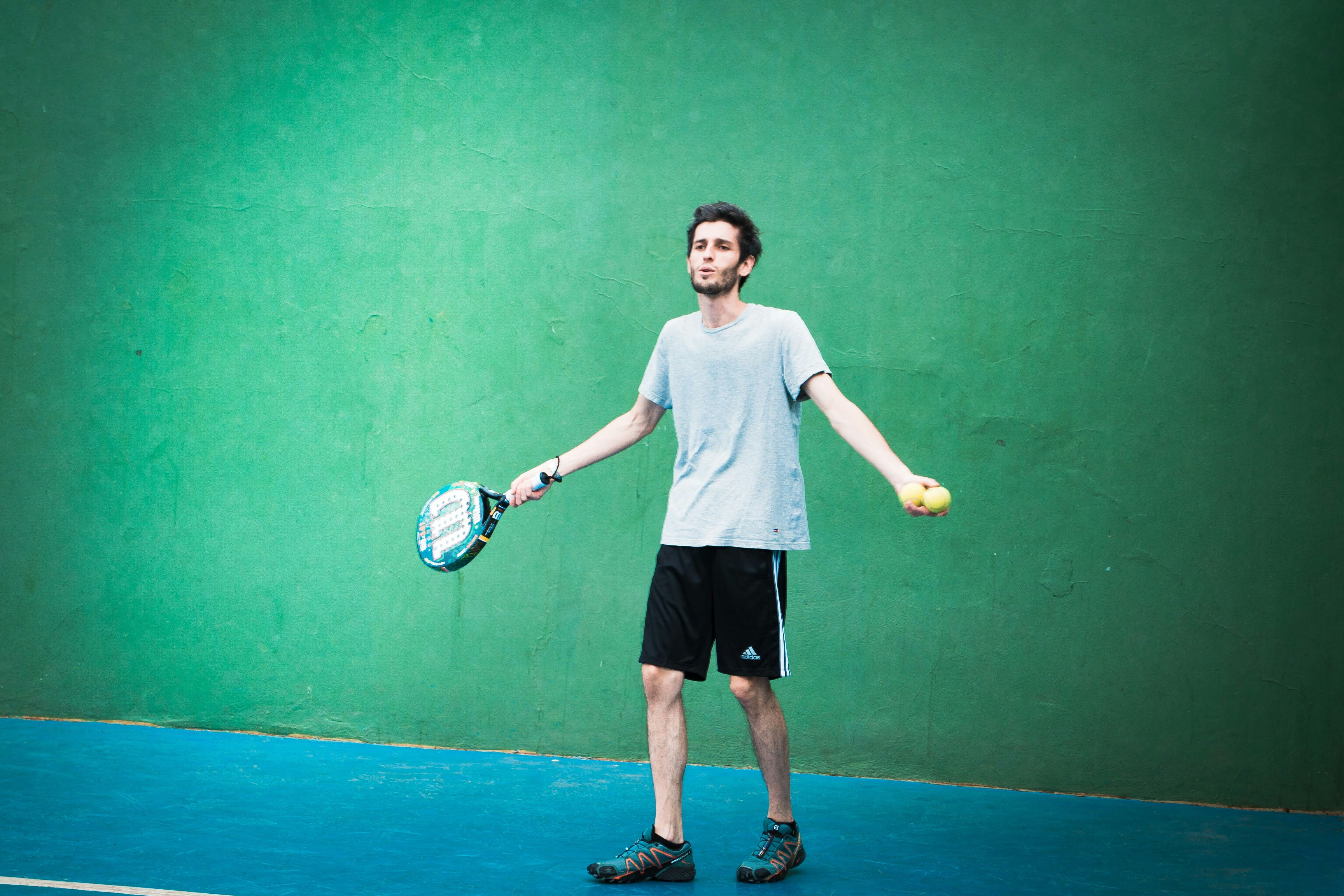 a man holding a tennis racquet and ball on a tennis court