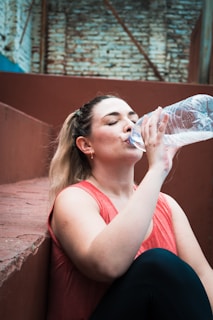 a woman drinking water from a plastic bottle