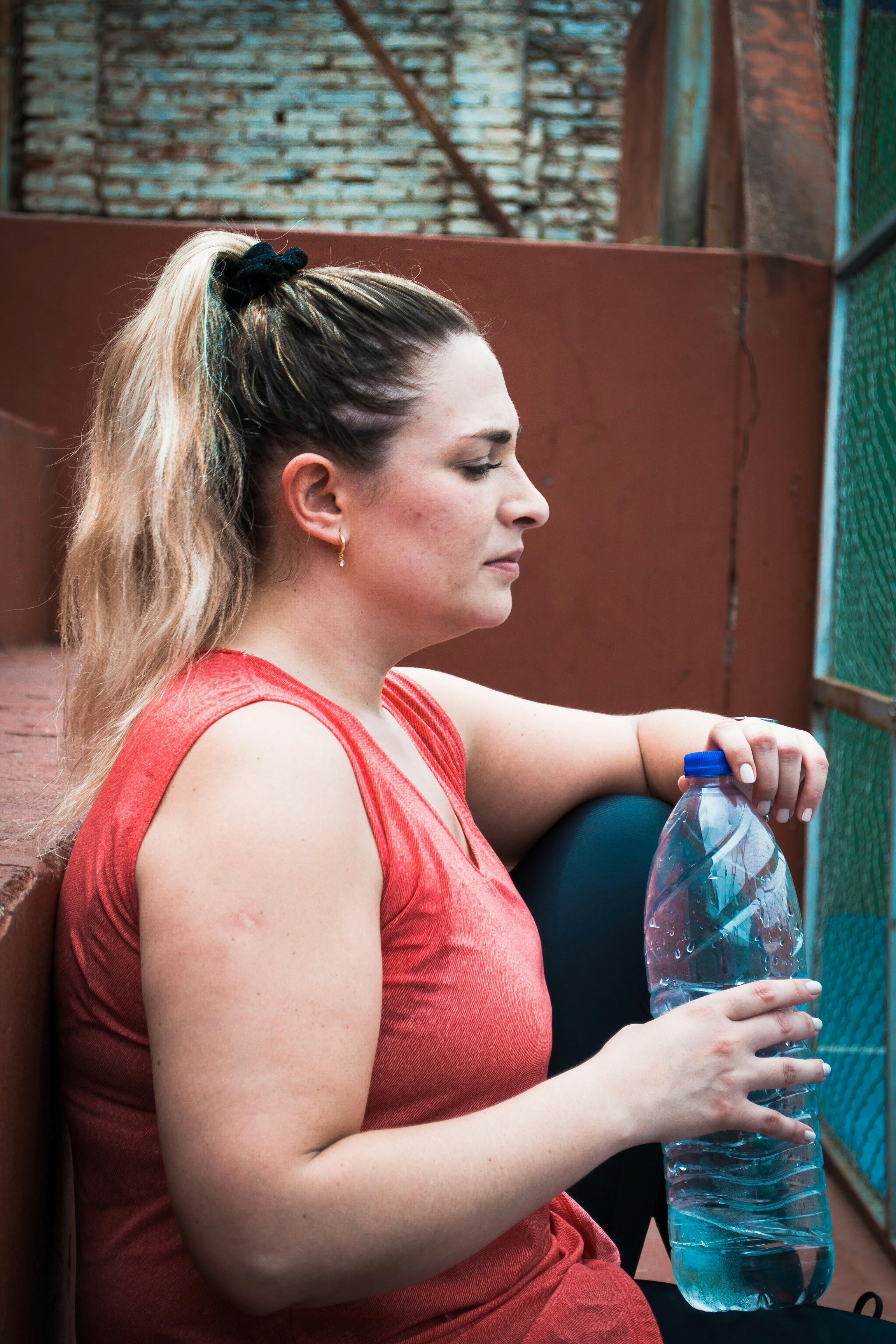 a woman sitting on a ledge holding a water bottle