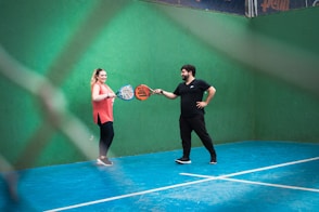 a man and woman holding tennis racquets on a tennis court