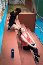 two women sitting on the steps of a tennis court