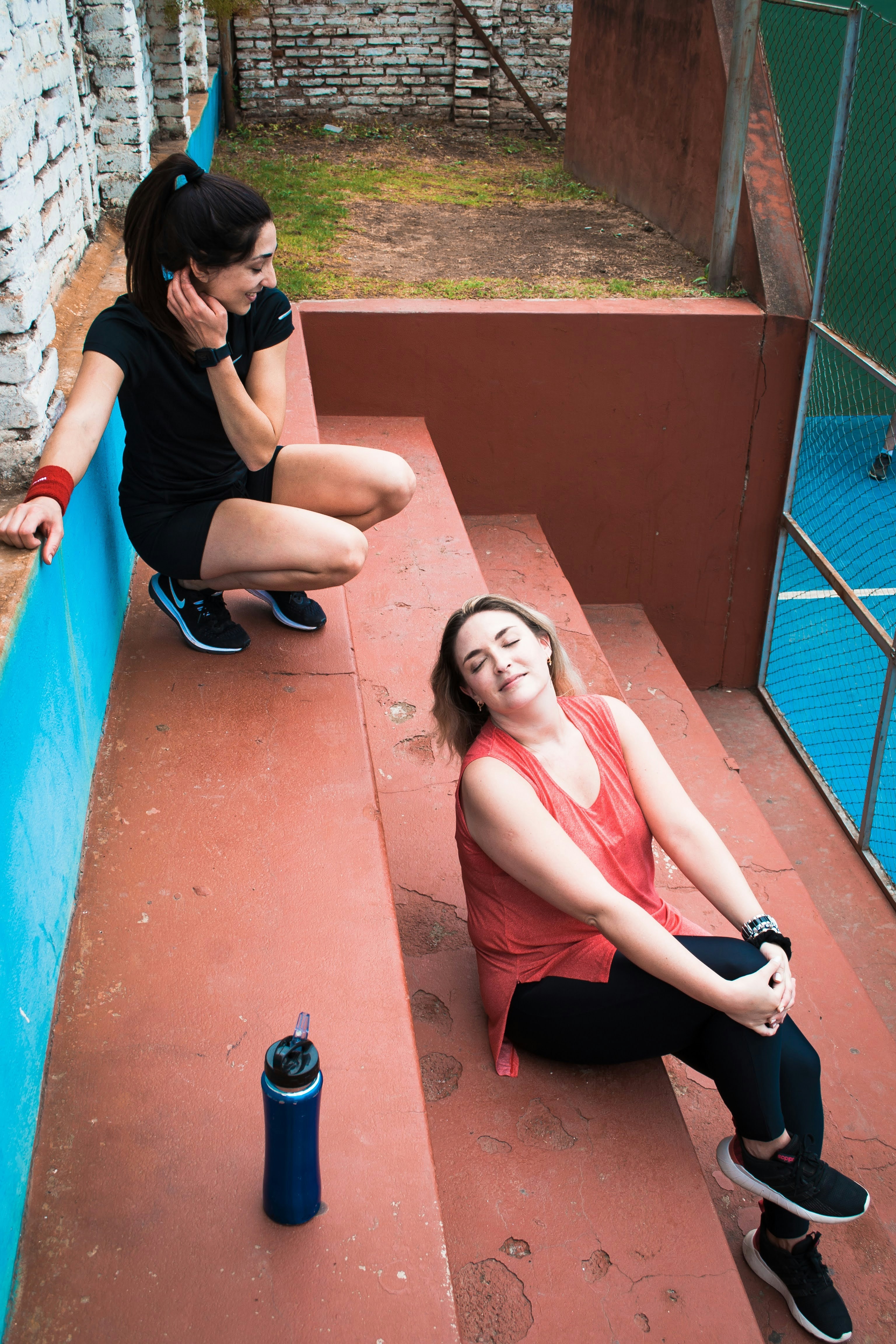 two women sitting on the steps talking on their cell phones
