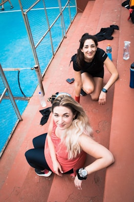 two young women sitting on the ground next to each other