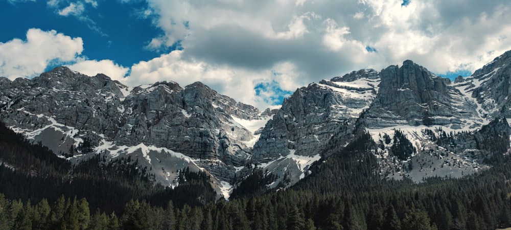 a mountain range with trees and clouds in the background