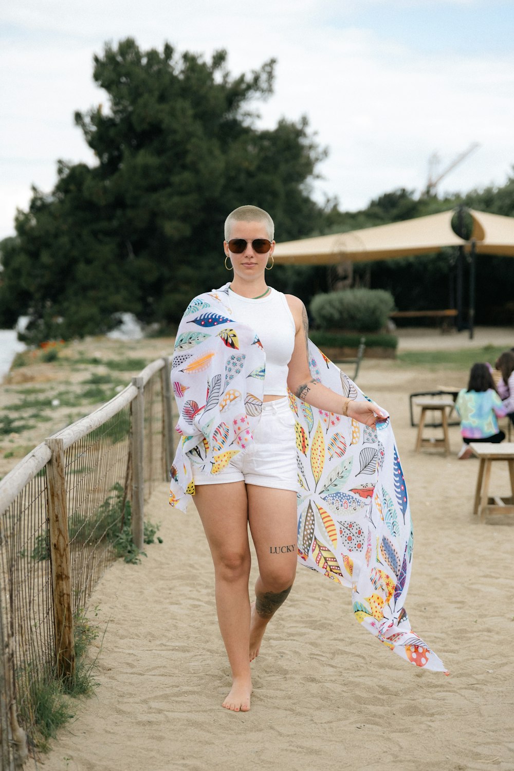 a woman walking on a beach carrying a colorful umbrella