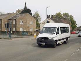 a white van driving down a street next to tall buildings