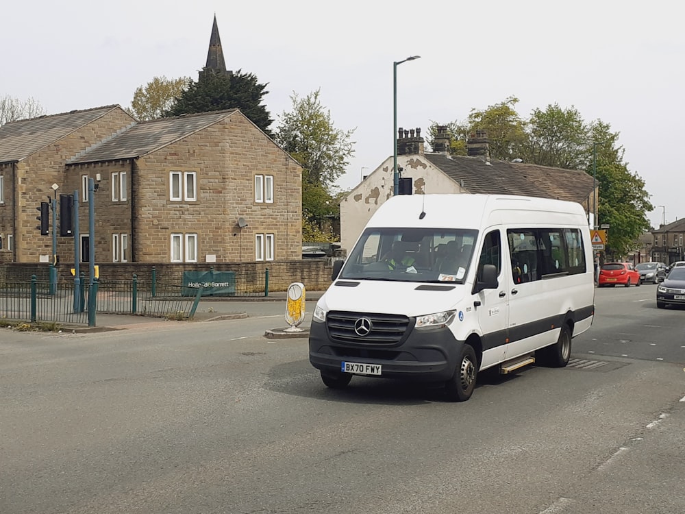 a white van driving down a street next to tall buildings